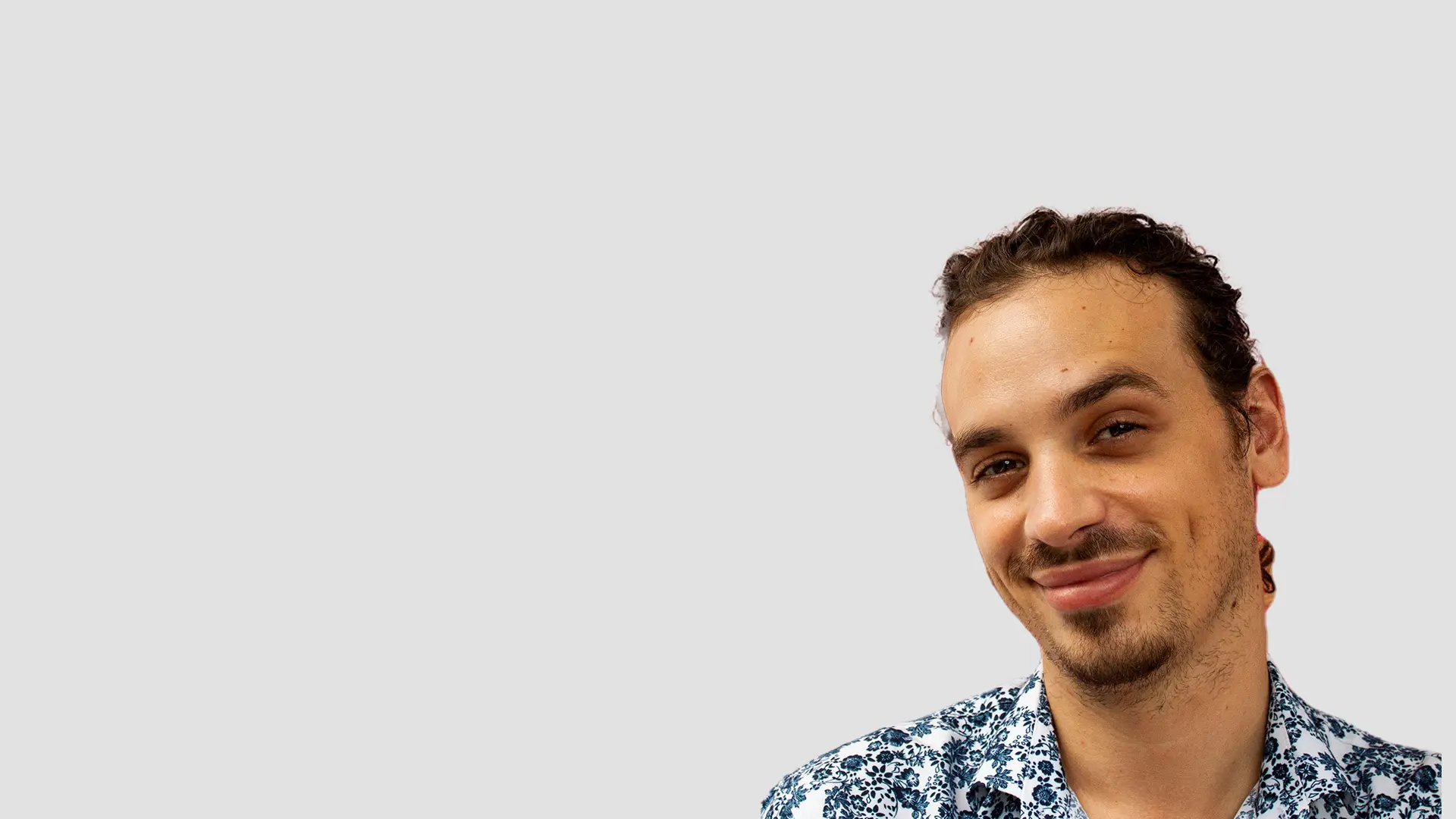 Homem sorridente vestindo camisa estampada floral azul e branca.