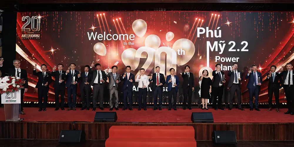 Groupe de personnes sur scène tenant des trophées lors de la cérémonie des 20 ans de Mekong Energy, avec un grand écran affichant “Welcome to the 20th Anniversary – Phú Mỹ 2.2 Power Plant”.