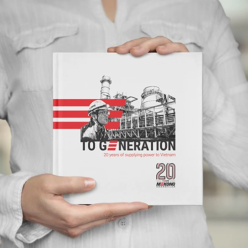 Livre intitulé "To Generation – 20 Years of Supplying Power to Vietnam", célébrant les 20 ans de Mekong Energy, tenu par une personne en chemise blanche.